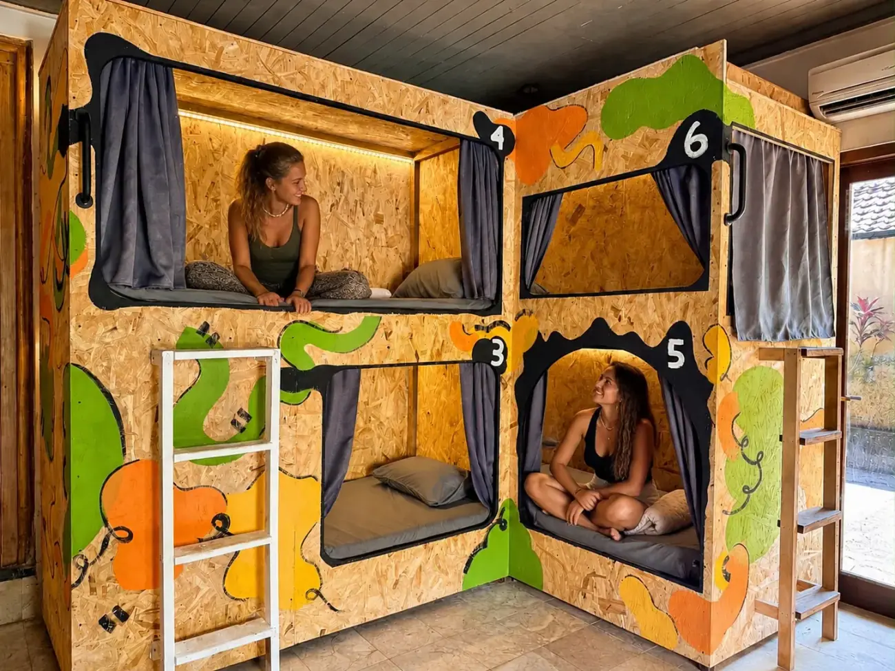 Two guests sitting in their pods in the orange and green dorm